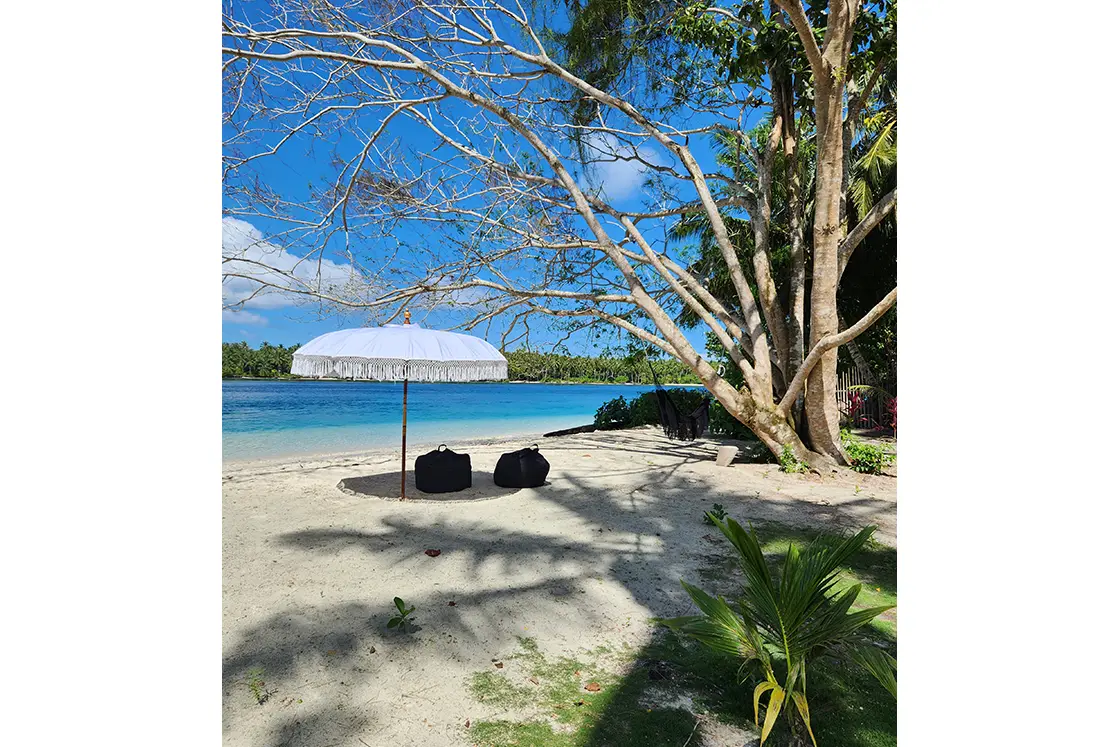Perfect Hideaways real estate property: A spacious bedroom with a four-poster bed, featuring open double doors to a lounge area, and decorative overhead lighting. Leleu Boutique Beach Villas, Mentawai.