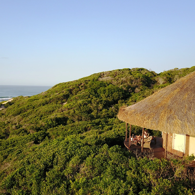 Perfect Hideaways real estate property: A lodge with a sea view and people sitting on the deck. Dunes de Dovela Lodge, Mozambique.