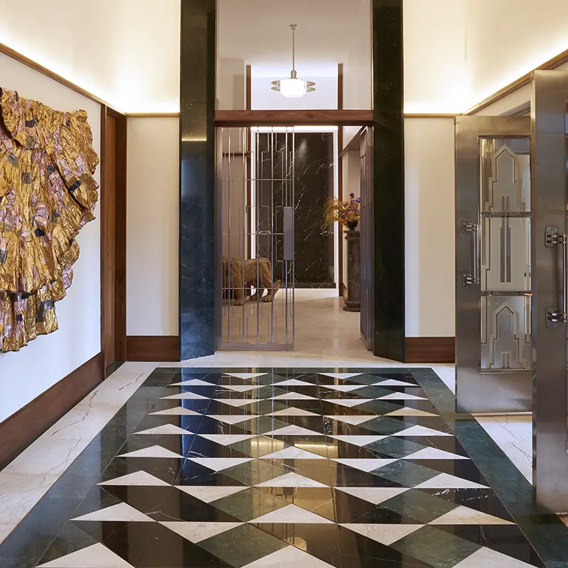 Perfect Hideaways real estate property: Art deco hallway with geometric black and white patterned floor, gold abstract wall art, elegant doors, and a soft-lit pendant lamp creating a sophisticated ambiance. The Assembly Room in Cape Town.