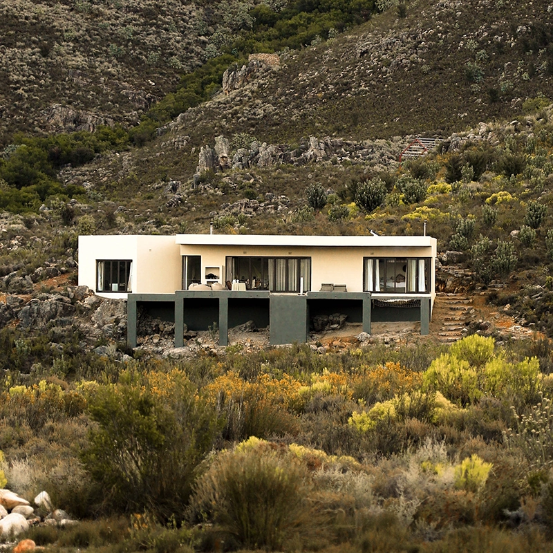 Perfect Hideaways property for sale: A two-storey solar-powered cabin on the slopes of the Hawequas mountains. The cabin is surrounded by dense shrub-like vegetation. Oomblik Cabin, Wellington.