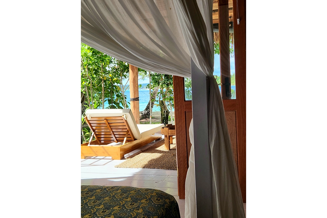 Perfect Hideaways real estate property: The bedroom of a tropical beachfront villa, showcasing nearby sun loungers and open plan design. Leleu Boutique Beach Villas, Mentawai.