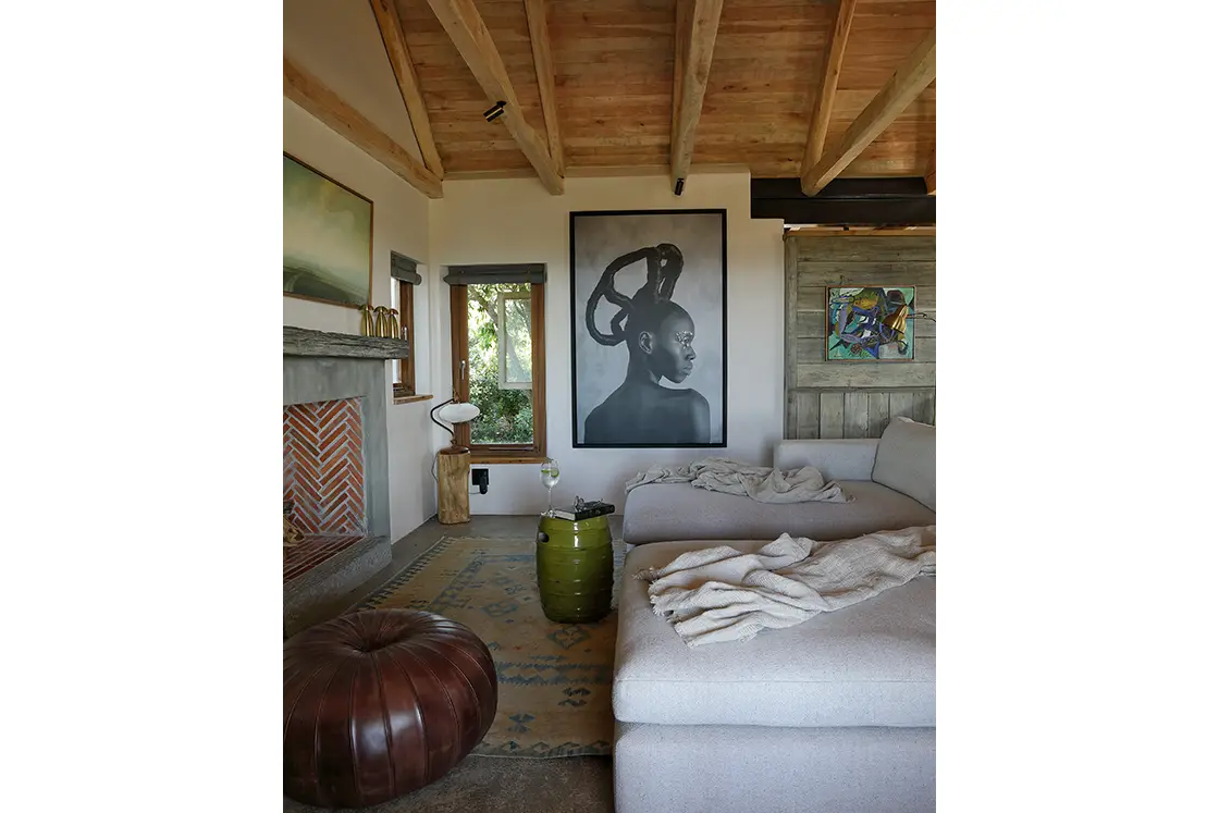 Perfect Hideaways property for sale: A side view of the living room showcasing a contemporary sofa, textured ottoman, warm throws, and artistic pieces, lit by soft natural light. Yellowwood Cottage, Churchhaven.