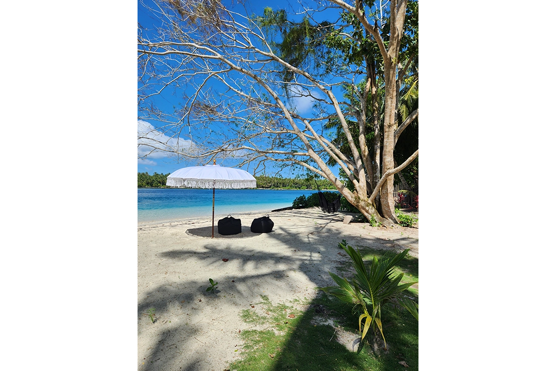 Perfect Hideaways real estate property: A spacious bedroom with a four-poster bed, featuring open double doors to a lounge area, and decorative overhead lighting. Leleu Boutique Beach Villas, Mentawai.