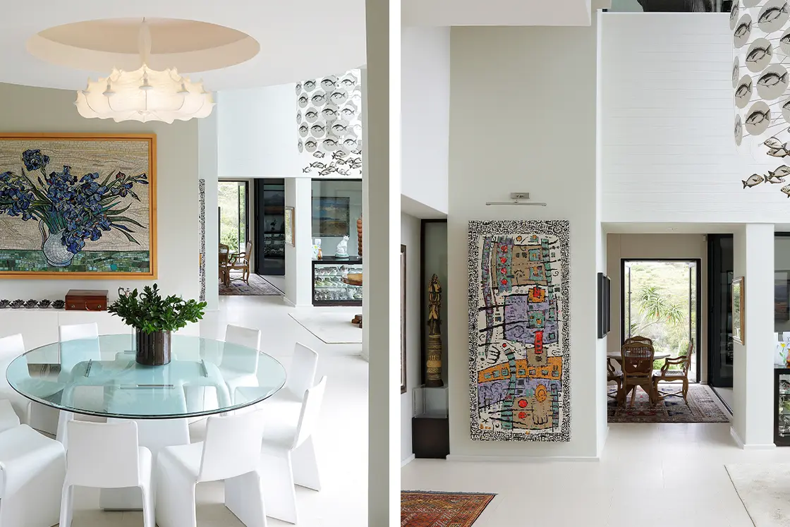 Perfect Hideaways real estate property: Modern dining area with a round glass table, white chairs, and a large floral artwork. Adjacent space features eclectic wall art and a cozy seating nook. Knysna, Ocean’s Edge.